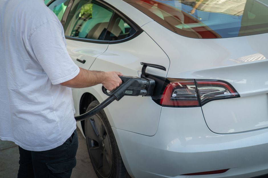 Electric car plugged into a home charger on a driveway