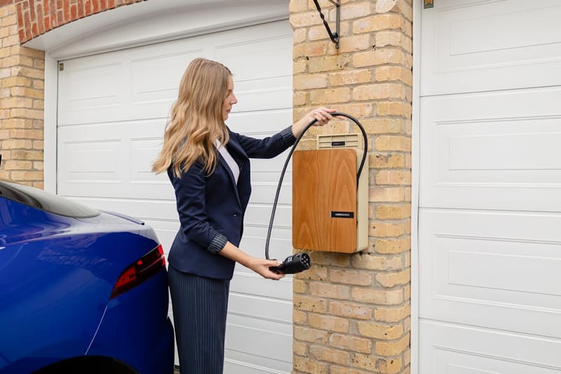 Andersen A3 home EV charger wall-mounted on a brick exterior, showing the integrated cable hider and sleek black front panel